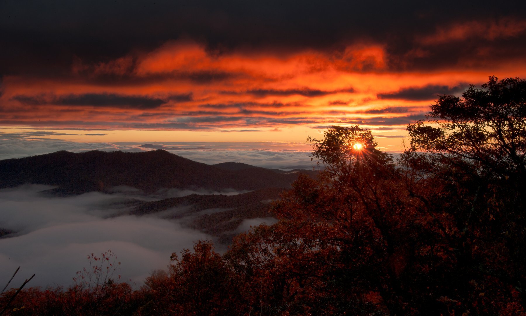 A fiery red sunset over the Blue Ridge Mountains, fog filling the valleys