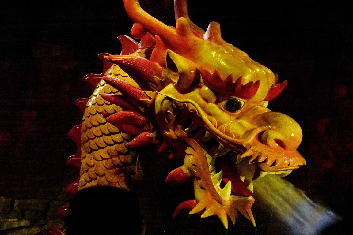 A carved golden dragon head lit against darkness